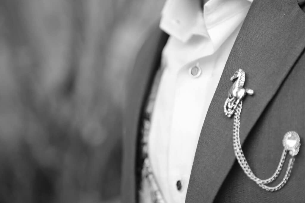 Statement Brooch - Stylish black and white close-up of a luxury horse brooch on a man's suit, highlighting elegance.