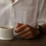 Your Coffee Crisis: Climate & Chaos Threaten Your Daily Brew - a person holding a cup of coffee