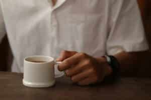Your Coffee Crisis: Climate & Chaos Threaten Your Daily Brew - a person holding a cup of coffee