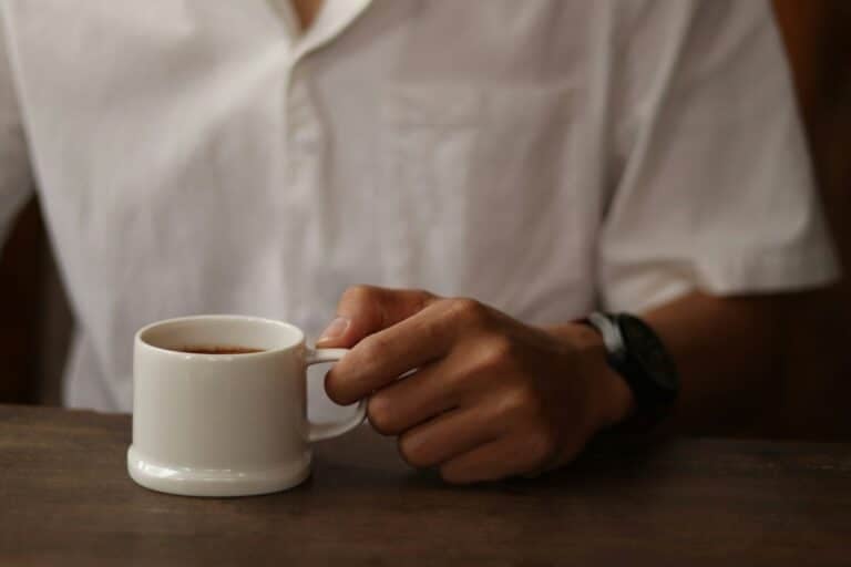 Your Coffee Crisis: Climate & Chaos Threaten Your Daily Brew - a person holding a cup of coffee